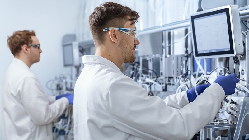 Fermentation scientists in a VALIDOGEN laboratory operating bioreactor systems for protein expression research..